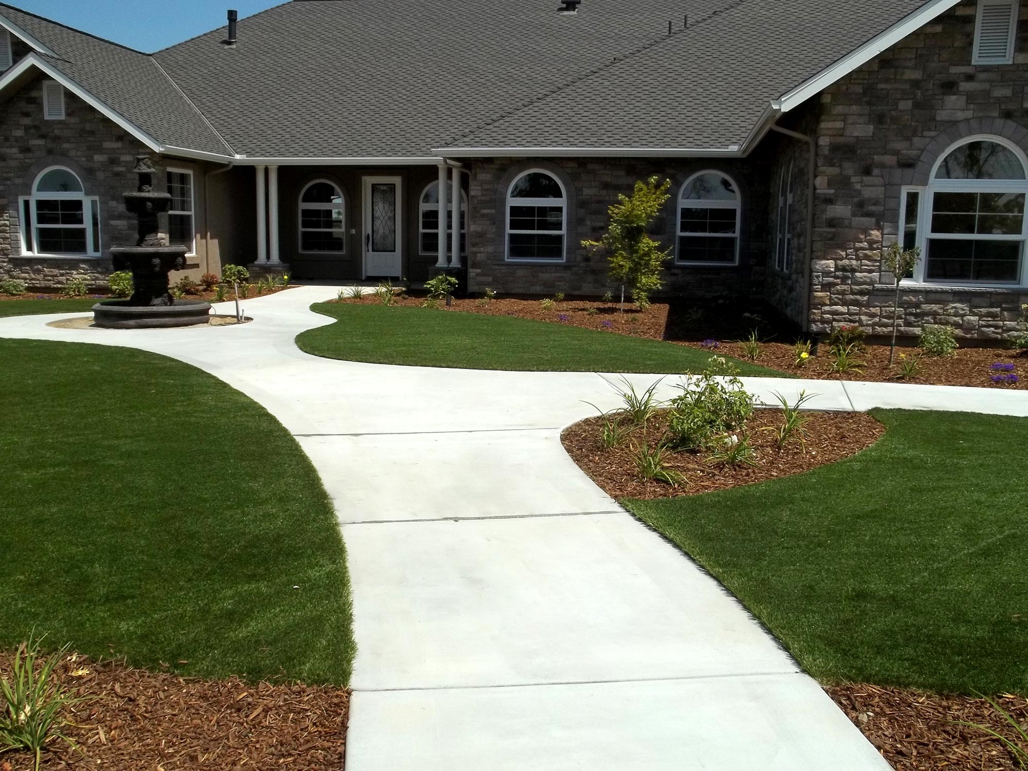 concrete walkway with custom landscaping and fountain